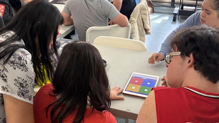Des personnes participent à un jeu-questionnaire sur une tablette électronique.