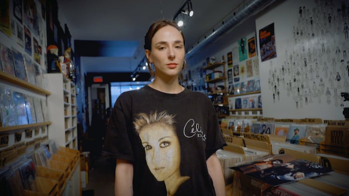 Une jeune femme sourit dans un magasin de disques. 