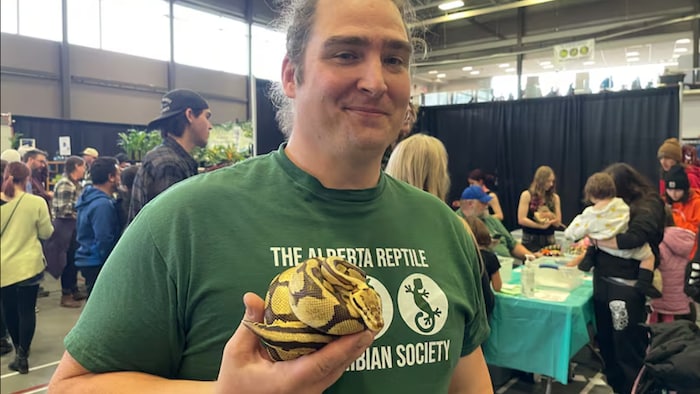 Cody Faulds, président de l'Alberta Reptile and Amphibian Society, sourit à la caméra dans un salon d'exposition. 