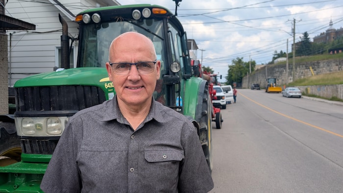 Denis Bouchard pose devant un tracteur dans les rues du centre-ville de Chicoutimi.