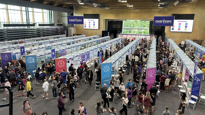 Des exposants dans une grande salle vue de haut.