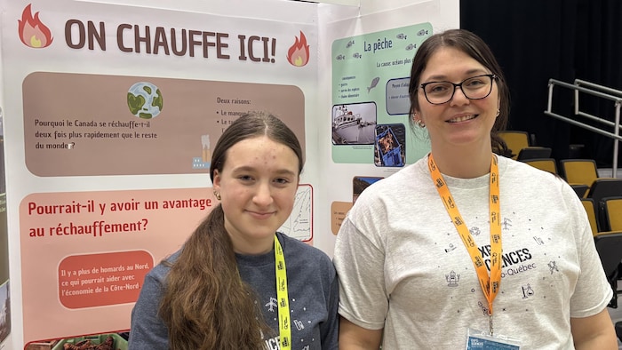 Charlotte Joncas et Delia Lavallée sourient devant leur affiche.
