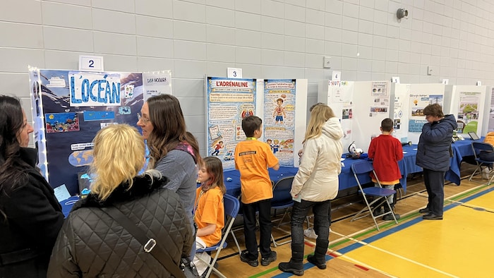 Des kiosques sont exposés dans un gymnase d'une école secondaire.
