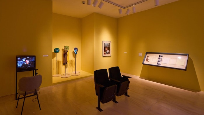 Une salle de musée montre quelques sièges et des articles exposés.