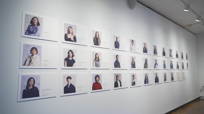 Les photos des 35 étudiants qui ont participé à l'exposition sont affichées sur un mur de l'exposition.