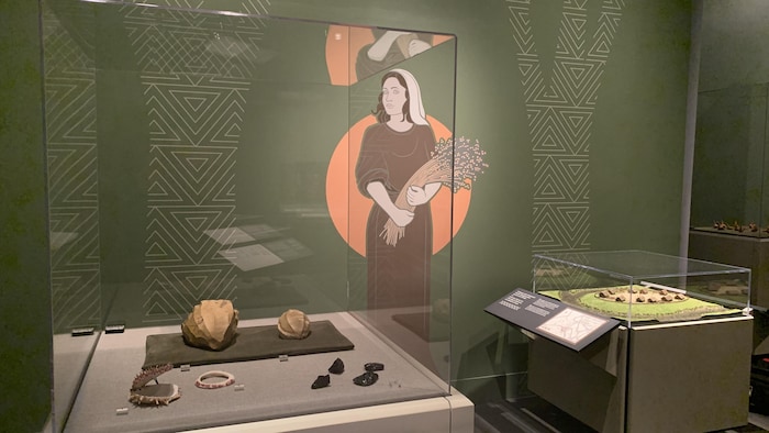 Des objets antiques protégés par des vitrines et un dessin mural dans un musée. 