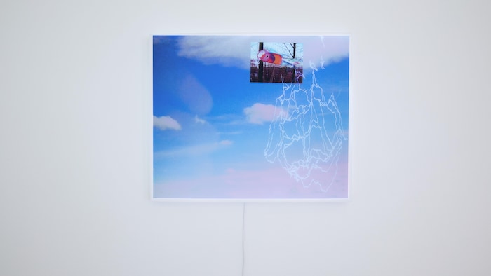 Capsule and breathway, 2026. OU Cette image incorpore un manche à air et un traçage d'un bateau qui flottent dans un ciel nuageux. À gauche, les doigts de l'artiste, sont en relief dans une fenêtre. Image de Daisy Wu © 2026.