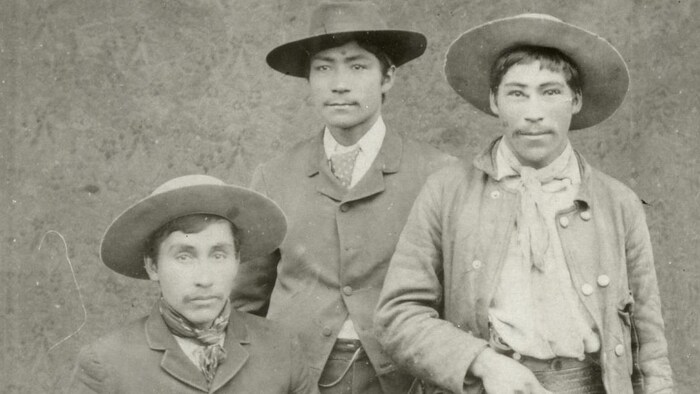Trois cowboys posent pour la caméra en 1885.