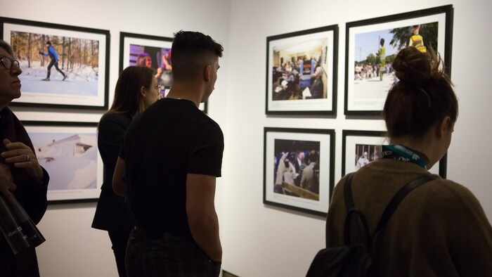 Des visiteurs regardent des photos accrochées au mur.