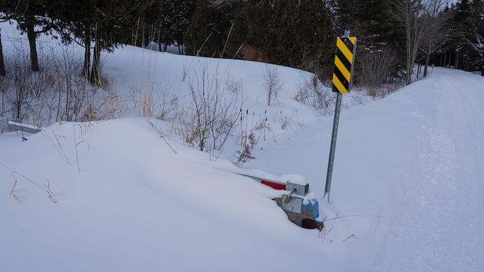 Un bloc de béton, une barrière et un cadenas sous la neige.