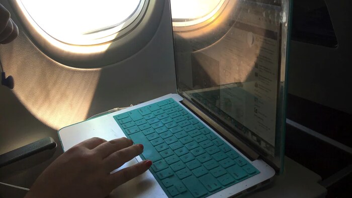 A passenger uses a laptop aboard a commercial airline flight from Boston to Atlanta on July 1, 2017. The airline cancellations come even after mobile phone carriers AT&T and Verizon say they will postpone new wireless service near some U.S. airports planned for this week. 
