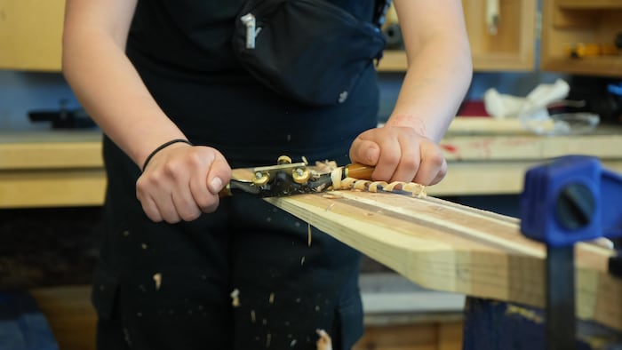 Un gros plan sur des mains qui sculpte une pagaie en bois.