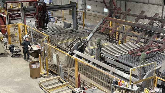Une machine fabrique du treillis métallique.