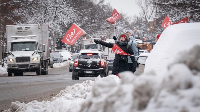 Des grévistes manifestent en bordure d'une route à Montréal.