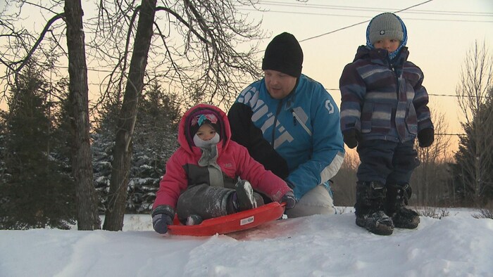 Evans Pedneault pousse ses enfants dans une luge sur une colline de neige pour glisser près de la maison familiale.