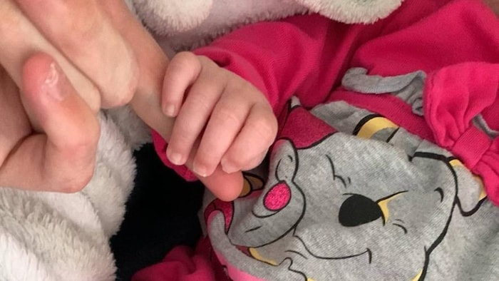 Le bébé tient le doigt de sa maman.