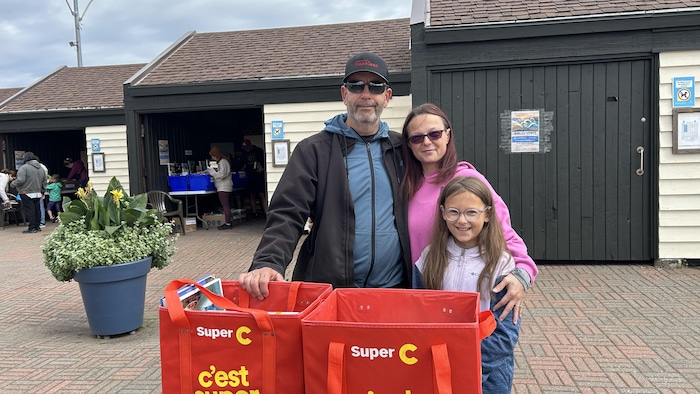La famille pose pour la photo devant les deux sacs.