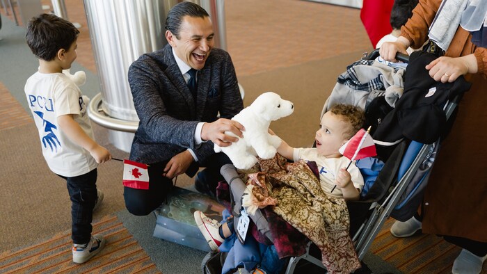Wab Kinew salue un enfant avec un ours polaire en peluche. 