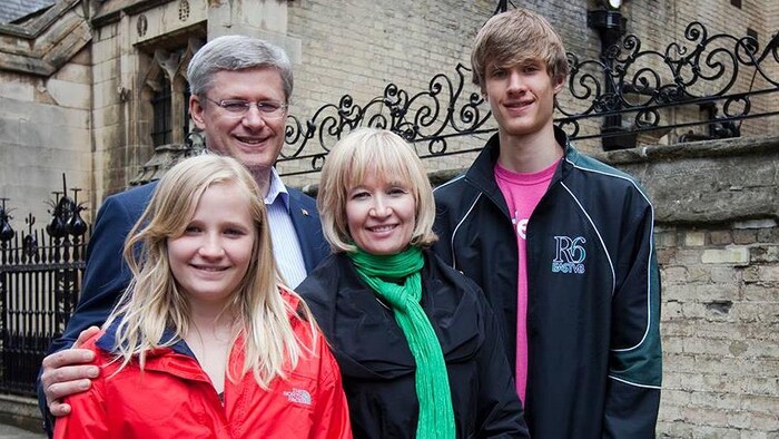 L'ancien premier ministre du Canada Stephen Harper pose pour la caméra avec sa famille devant un immeuble en pierre. 