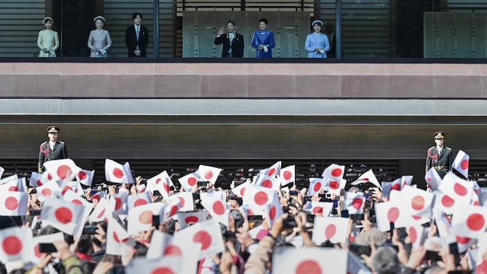 Des sympathisants agitent des drapeaux nationaux alors que l'empereur Naruhito du Japon (3e à droite en haut) fait son apparition aux côtés de l'impératrice Masako (2e à droite), de leur fille la princesse Aiko (à droite), du prince héritier Akishino (3e à gauche), la princesse héritière Kiko (2e à gauche) et leur fille, la princesse Kako (à gauche), sur le balcon du Palais impérial à l'occasion du 65e anniversaire de l'empereur, à Tokyo, le 23 février 2025.