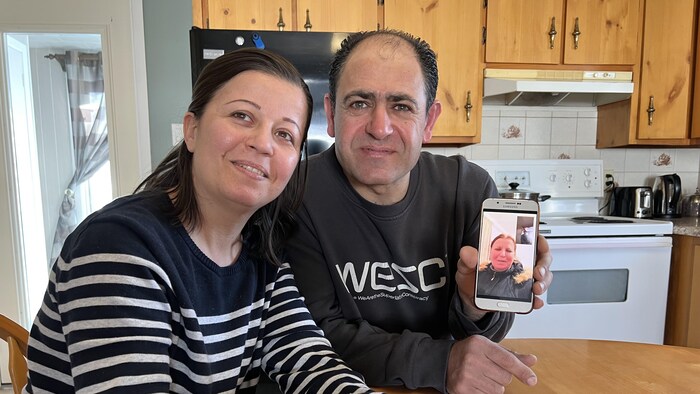 Deux Syriens montrent sur leur téléphone la famille avec laquelle ils sont en communication.