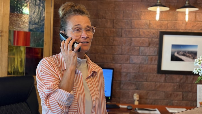 Fannie Bouchard est au téléphone, derrière un comptoir d'accueil.