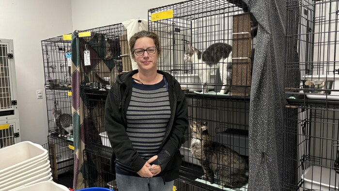 Fanny Veilleux debout entourée de chats dans leur cage.
