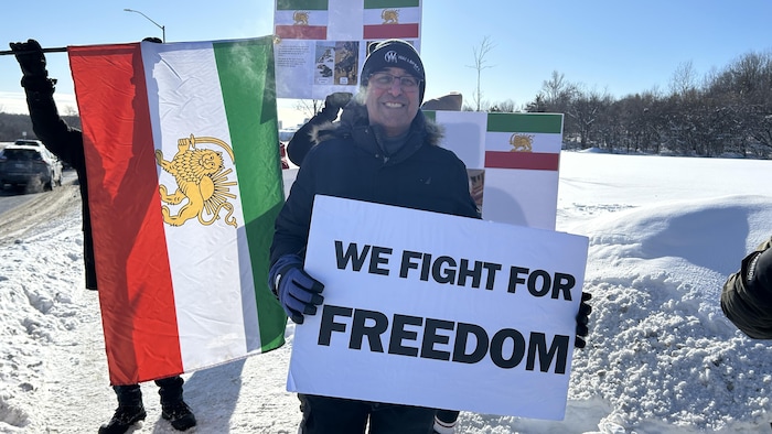 Photo de Faramarz Kord avec une pancartye dans la main. 