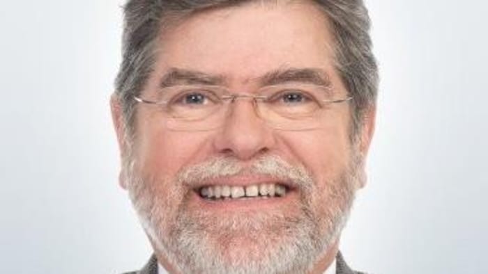 Serge Dubois sur fond blanc souriant devant l'objectif.