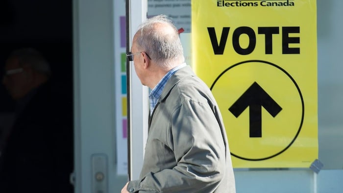 Un hombre junto a una mesa electoral en las elecciones federales de 2019.