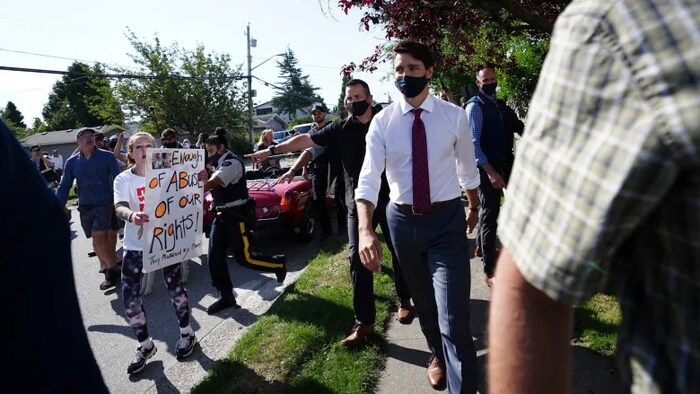 A protester yells at Liberal Leader Justin Trudeau as he makes his way to a motorcade in Surrey, B.C., on Wednesday, Aug 25, 2021.