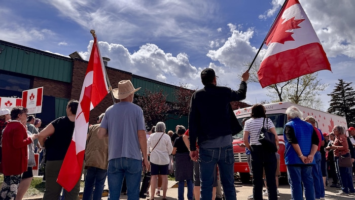 Deux personnes tiennent des drapeaux du Canada à Edmonton le 23 mai 2026.