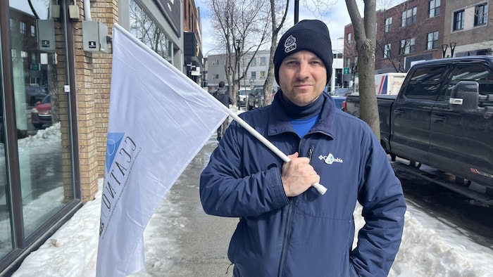 Félix-Antoine Lafleur tient un drapeau du Conseil central d'Abitibi-Témiscamingue–Nord-du-Québec dans ses mains.