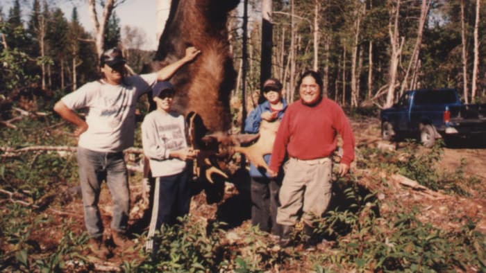 Quatre personnes, dont deux enfants et deux adultes, tous des hommes, dont Félix Atencio-Gonzales et Deven James Condo Mitchell lors d'une journée de chasse. Un orignal est sur la photo aussi. 