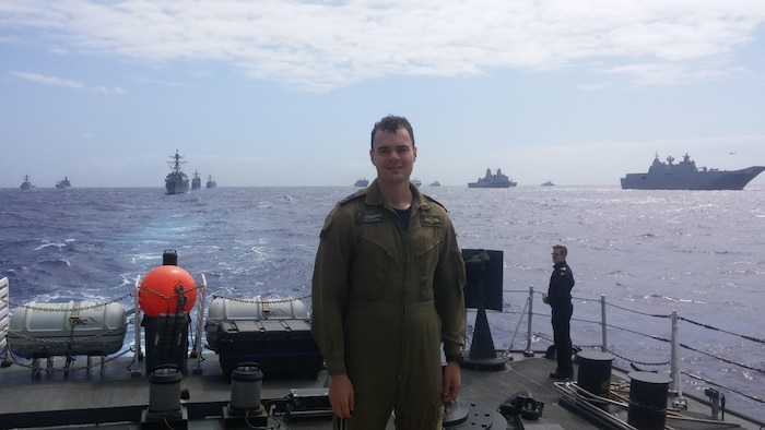 Le pilote se fait prendre en photograph sur le pont arrière d'un navire de la Marine royale canadienne au sein d'une flotte en déplacement.