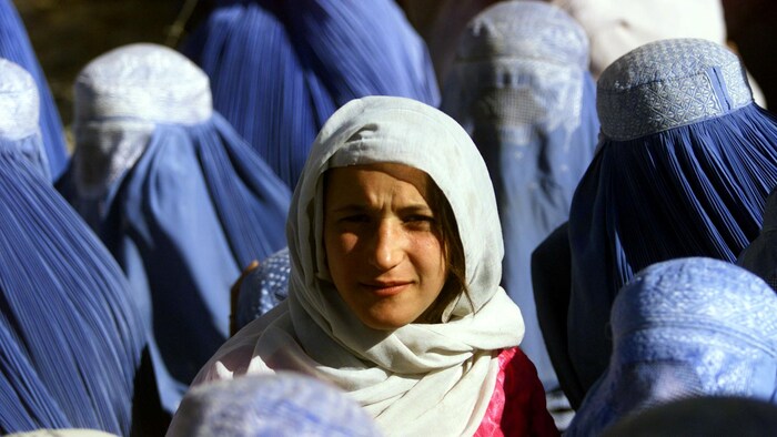 Una joven afgana con el rostro descubierto está rodeada de mujeres que llevan el burka, un vestido que cubre el cuerpo y la cara por completo.
