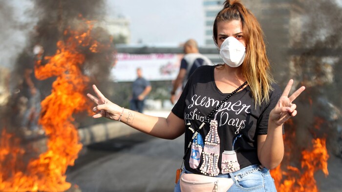 Une jeune femme blonde devant des pneus brûlés.