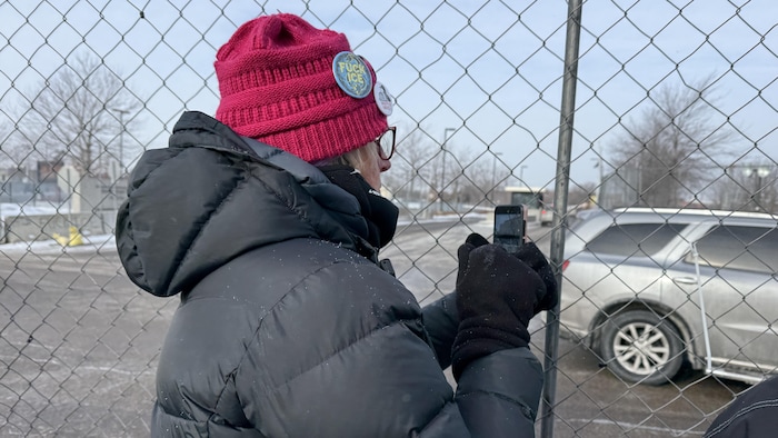 Une femme, chaudement habillée, tenant son téléphone.