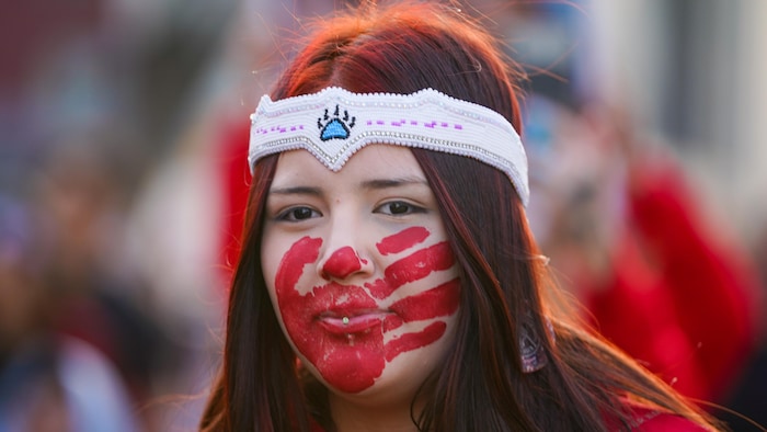 Une femme autochtone avec une main rouge sur la bouche. 