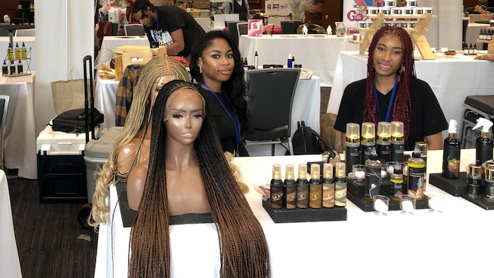 Deux femmes assises derrière leurs produits d'huile pour les cheveux.