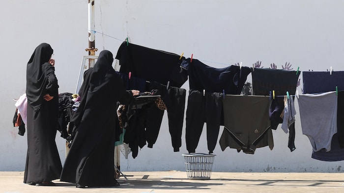 Des femmes étalent du linge sur une corde accrochée dans un refuge pour déplacés à Saïda, dans le sud du Liban.