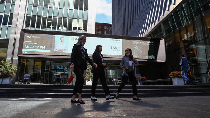 Trois femmes marchent dans le quartier des affaires au centre-ville de Toronto par une belle journée de septembre 2021.