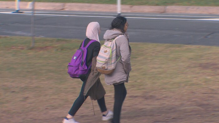 Deux étudiantes, dont une portant un hijab, marchent sur un campus
