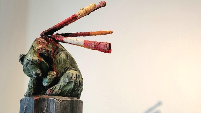 Sculpture de bois d'un ours avec des lances dans le dos.