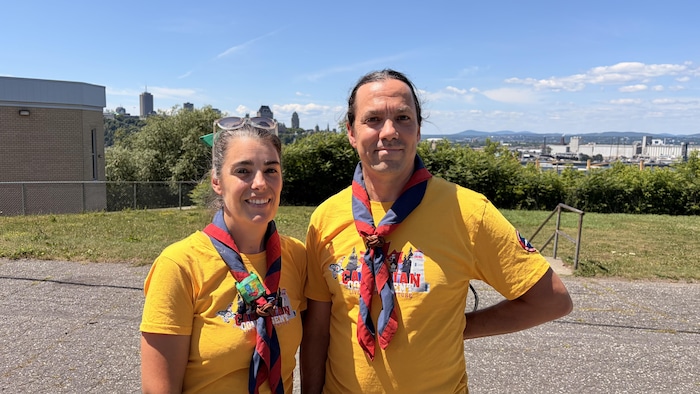 Deux animateurs scouts, dont Olivier Perron, sourient à la caméra dans leur stationnement.