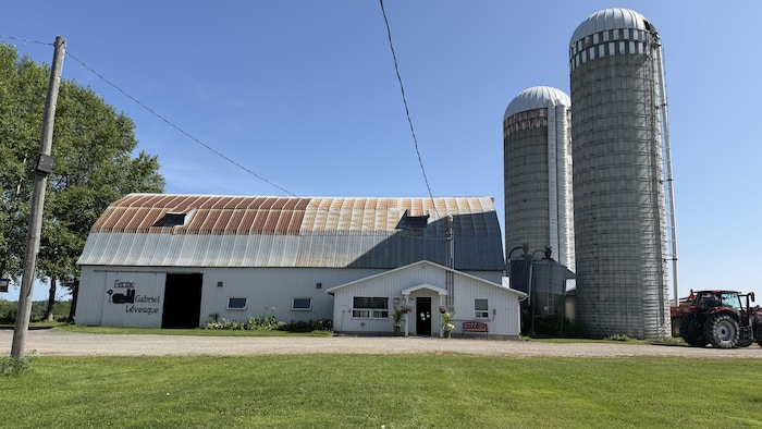 La bâtisse de la ferme avec deux silots à la droite de la bâtisse.