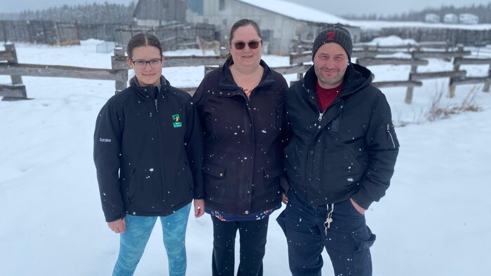 une fille, une femme et un homme debout dans la neige