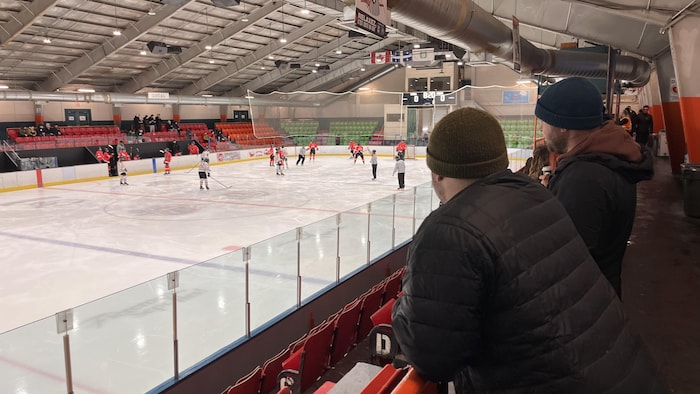 Des parents présents à une partie de Hockey qui se déroule sur la glace.