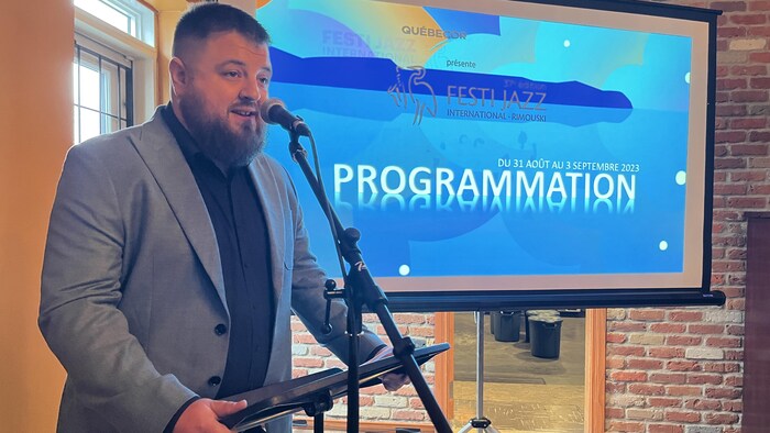 Sébastien Fournier derrière un lutrin lors de la présentation de la programmation du Festi Jazz dans un café à Rimouski.