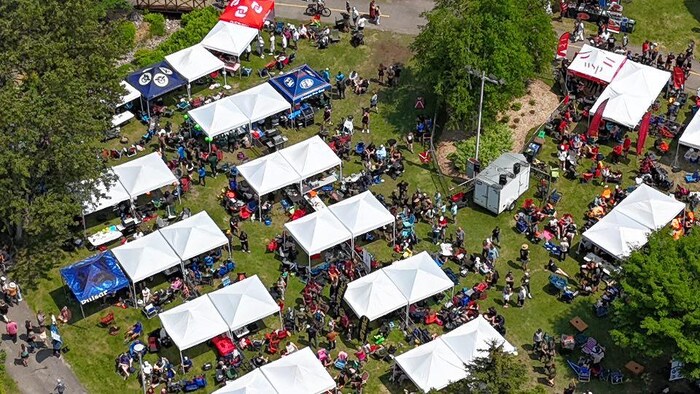 Vue aérienne d'un parc où sont visibles des dizaines de personnes et des petits chapiteaux.